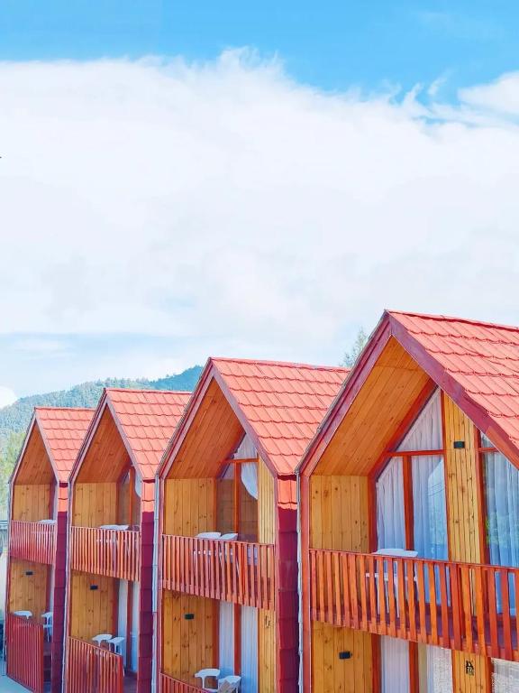 a row of wooden buildings with red roofs at Miarzafa Cabin House DIENG in Kejajar