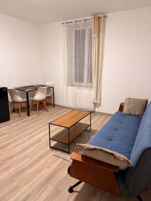 a living room with a blue couch and a table at 4-person apartment in Joeuf