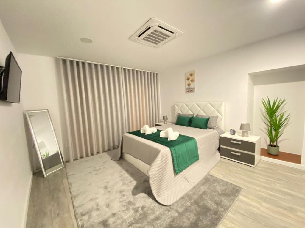 a bedroom with a white bed with a green blanket at Casa do Pelourinho in Arcos de Valdevez