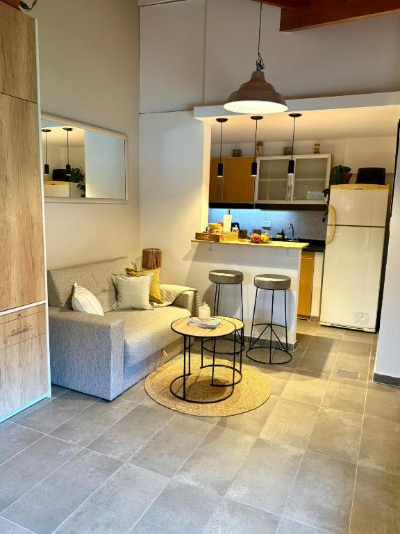 a living room with a couch and two tables and a kitchen at Espacio Nidra - Tu descanso a pasos del Aeropuerto in Ezeiza