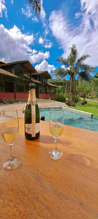 a bottle of wine and two glasses on a table at Pousada Vale da Cachoeira in Visconde De Maua