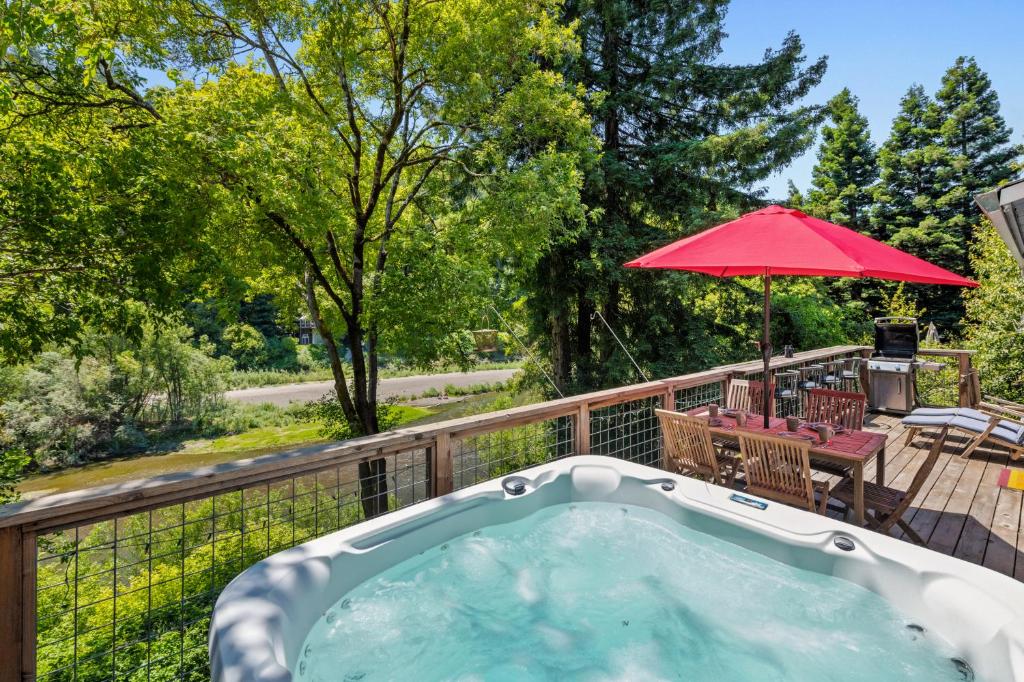 a hot tub on a deck with an umbrella at Moondance in Monte Rio