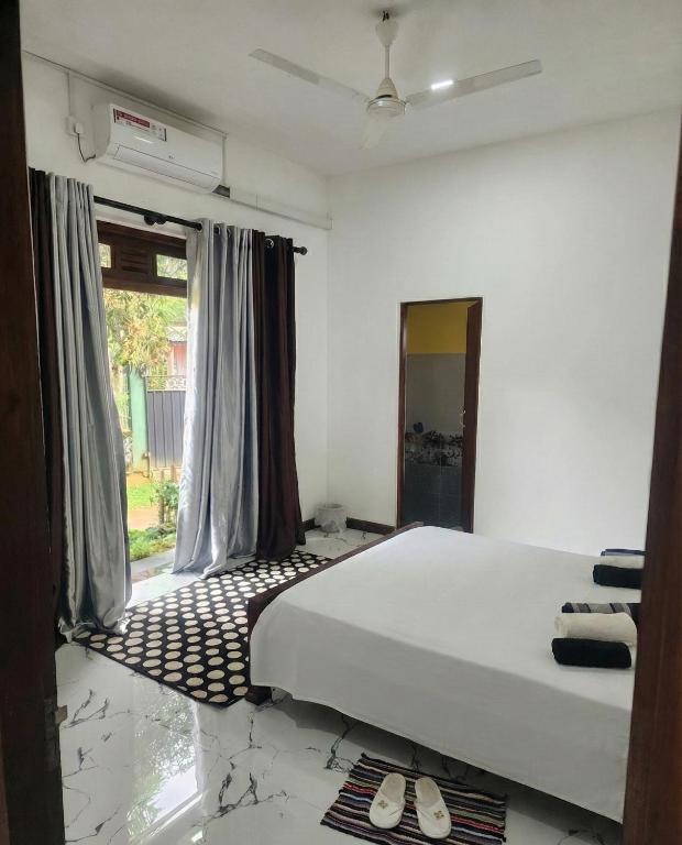 a bedroom with a white bed and a window at Villa kresilda in Gampola
