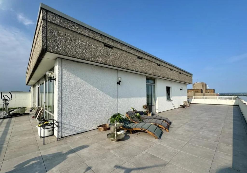 a patio with couches and a fence on a building at Rheinpanorama Penthouse Neuss Düsseldorf in Neuss