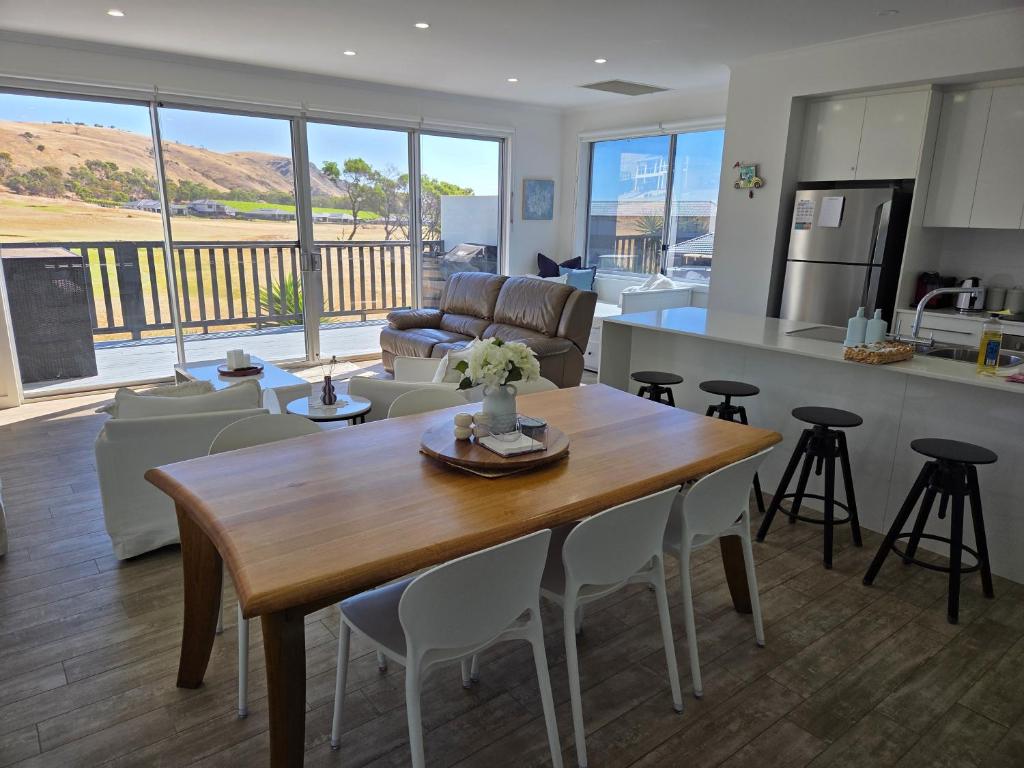 a kitchen and living room with a wooden table and chairs at 3rd On Troon in Normanville