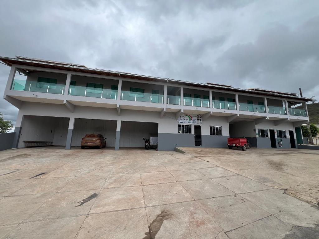 a large building with a car parked in front of it at Hotel Serrinha in Botumirim