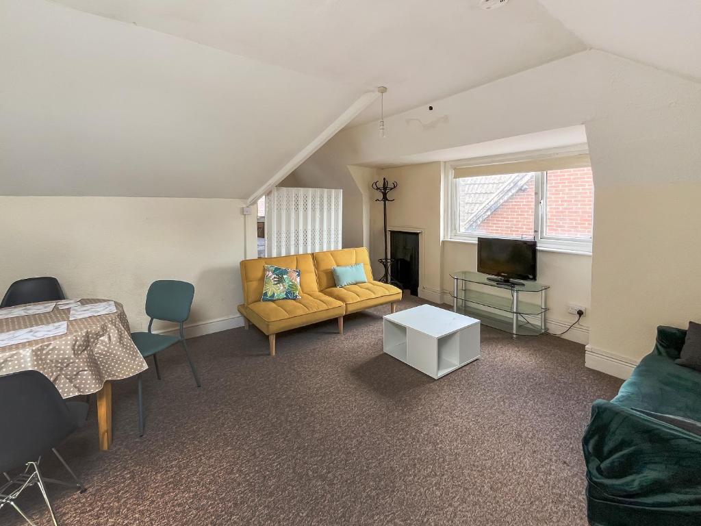 a living room with a yellow couch and a tv at Sunset In Southampton in Southampton