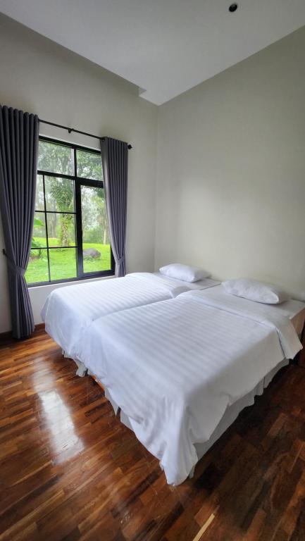 a large white bed in a bedroom with a large window at Cypress Resort Cipanas in Barukupa