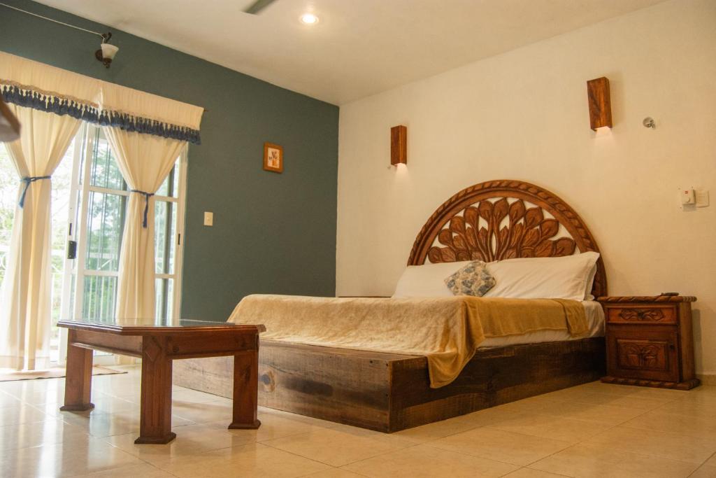 a bedroom with a bed with a wooden headboard at Casa X'Lapac in Valladolid