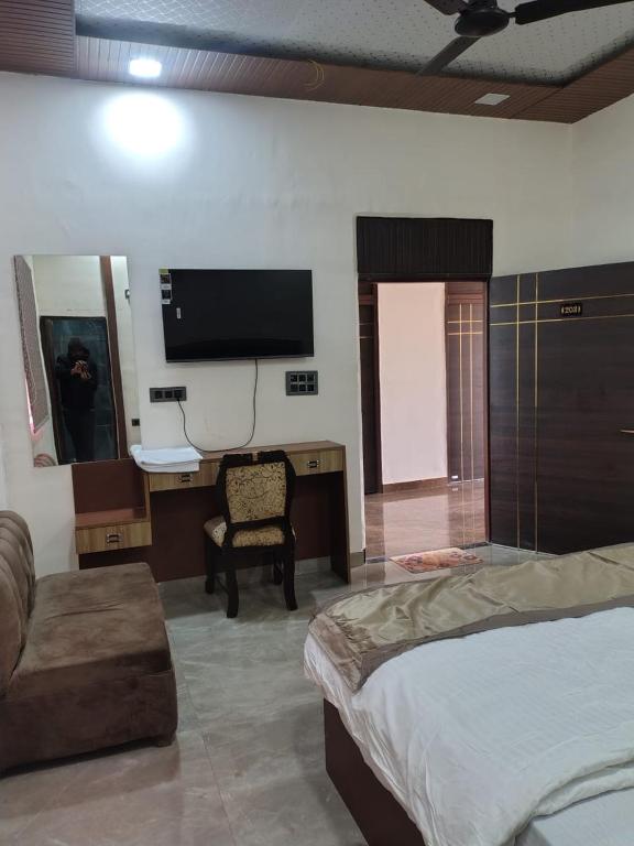 a bedroom with a bed and a tv and a chair at Lords Hotel in Agra