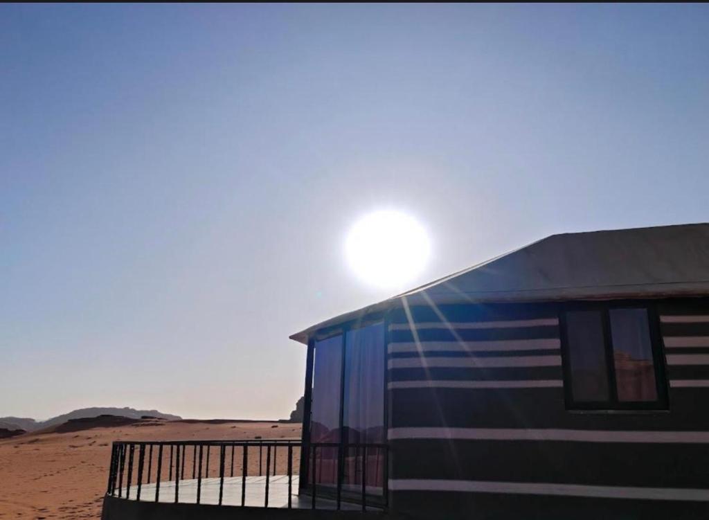 a building in the desert with the sun behind it at Starlit Wadi Rum camp in Wadi Rum