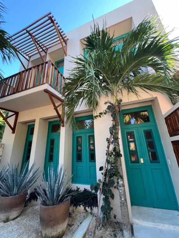 a house with green doors and palm trees at T'uut' Hotel in El Cuyo