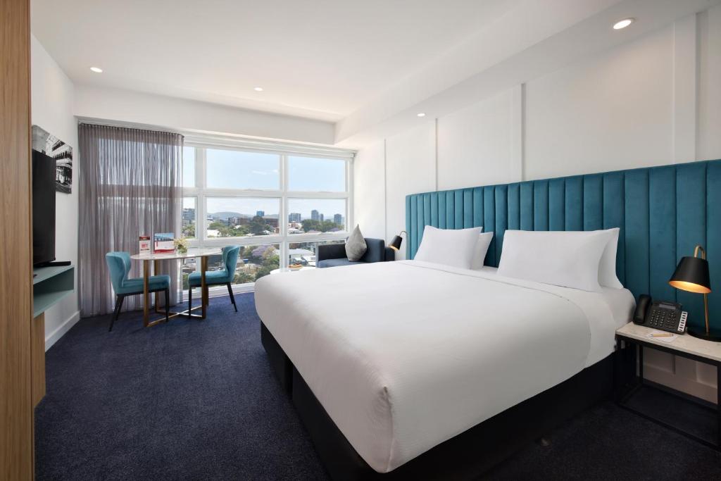 a hotel room with a large bed and a desk at Swiss-Belhotel Woolloongabba, Brisbane in Brisbane