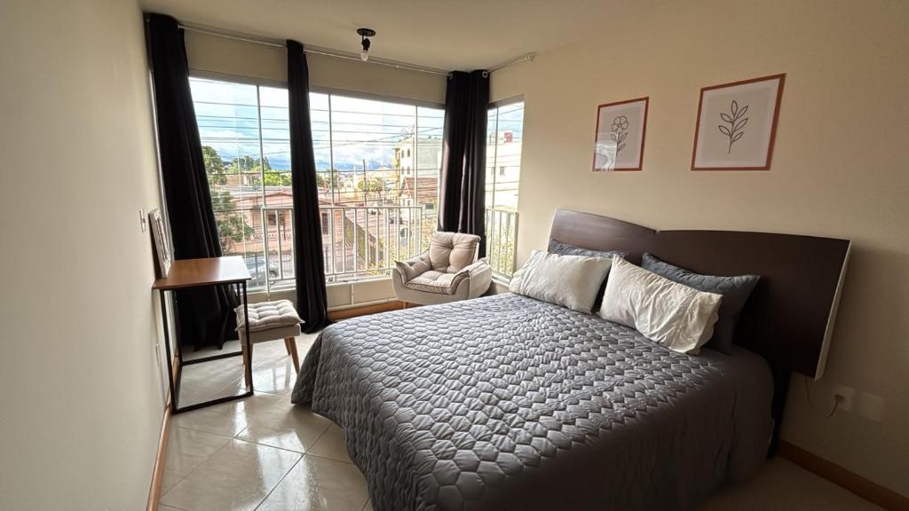 a bedroom with a bed and a large window at Apartamento no Centro 2 Wi-Fi Garagem in Vacaria