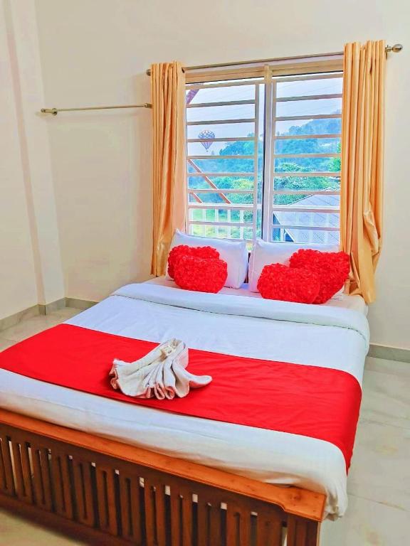 a bed with red flowers and a window in a room at Mount Teena in Anachal