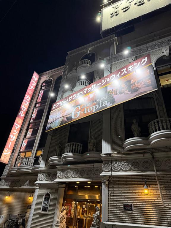 a building with a sign on it at night at Capsule Hotel Sauna G -topia male Only in Funabashi