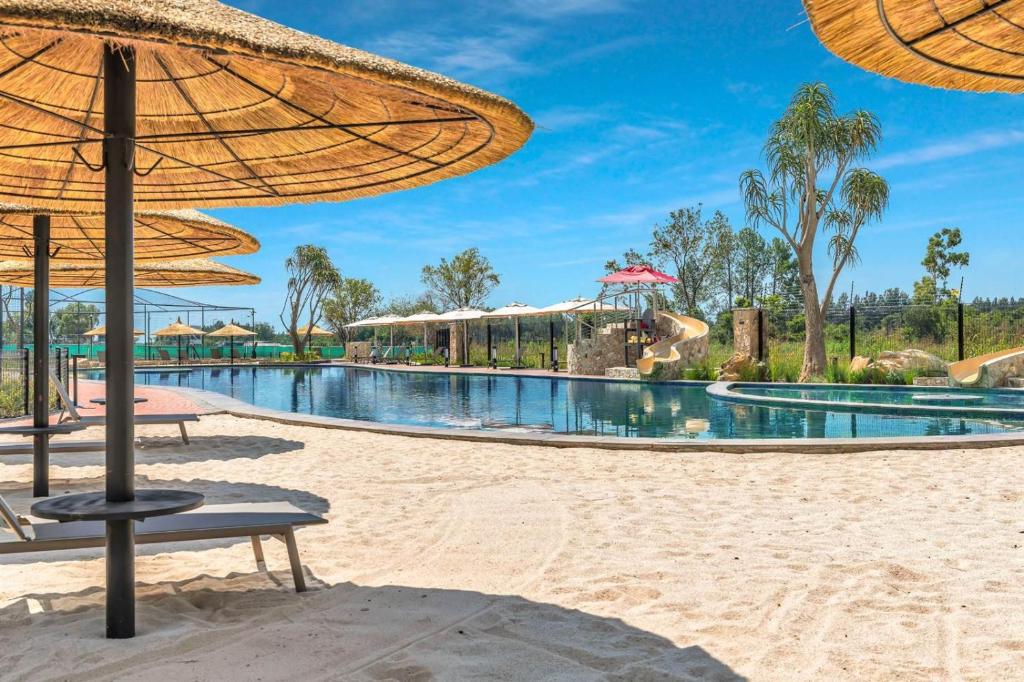 a resort pool with umbrellas on the beach at Lagoon Aparthotel in Pretoria