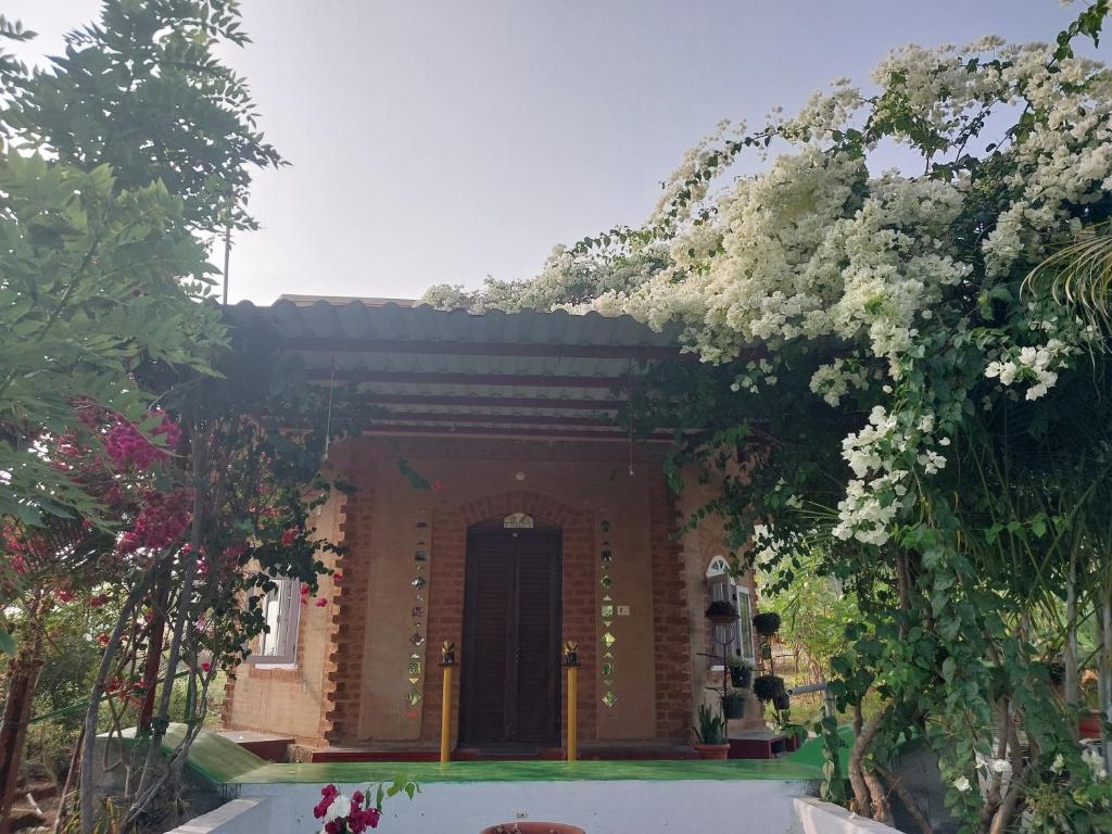 a brick building with a door and flowers at Aalamaram Farm in Anchetti