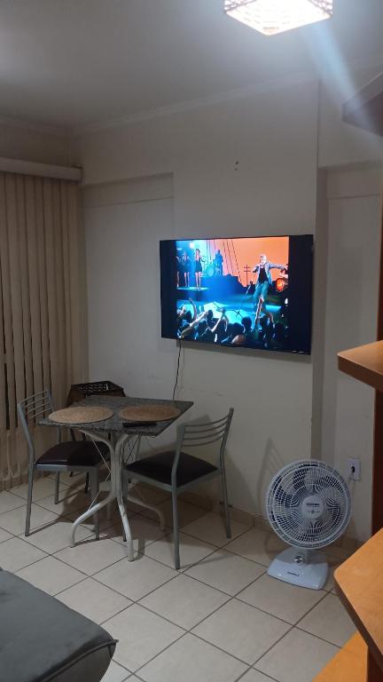 a dining room with a table and a tv on the wall at Apartamento suite central 72 in Franca