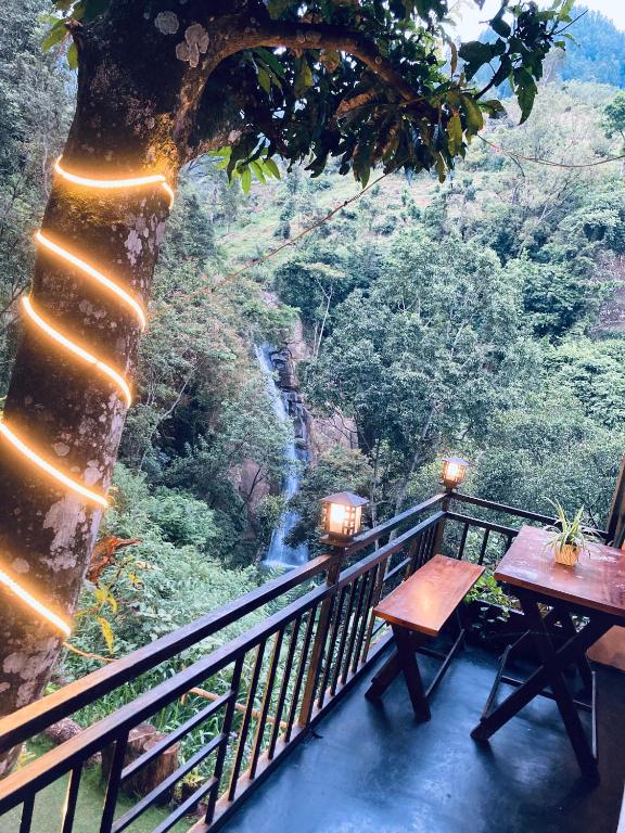 a balcony with tables and a waterfall in the background at Downtown Lodge in Nuwara Eliya