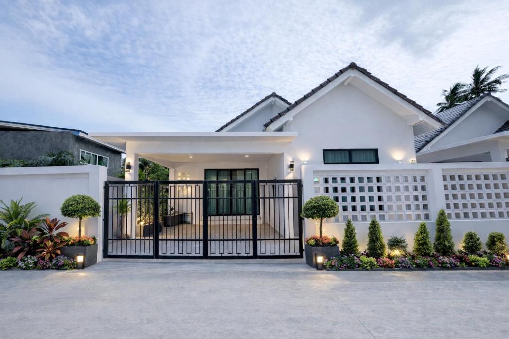 a white house with a black gate at Labelle villa koh phangan in Ko Phangan