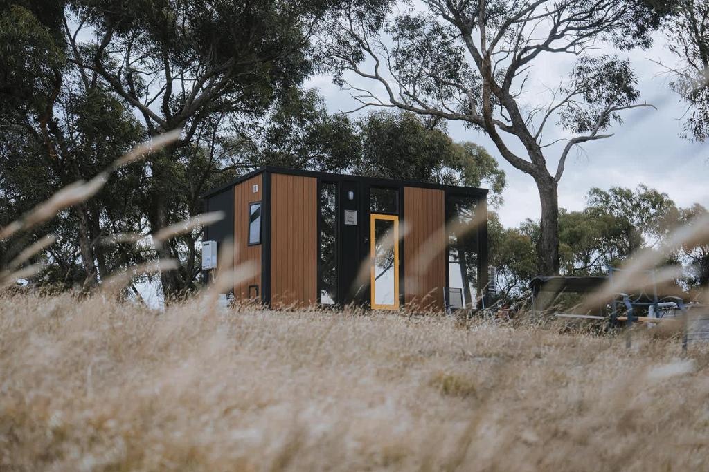 a tiny house sitting in a field of grass at Tallarook Hilltop Tiny House 1 by Tiny Away in Tallarook