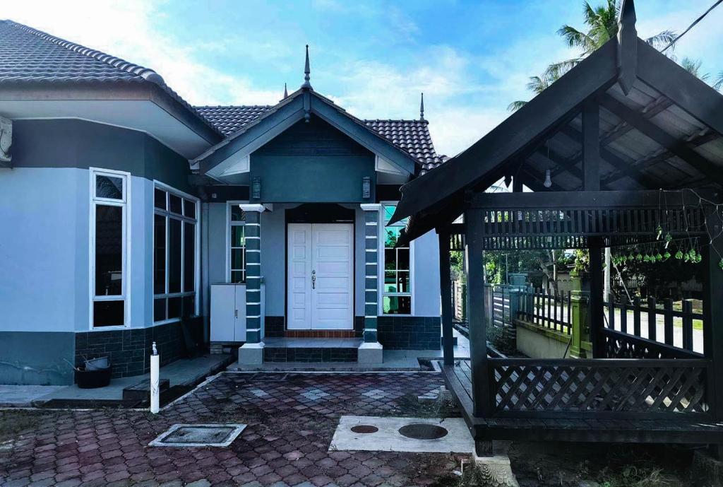 a house with a white door and a fence at Azihar Homestay Marang in Marang