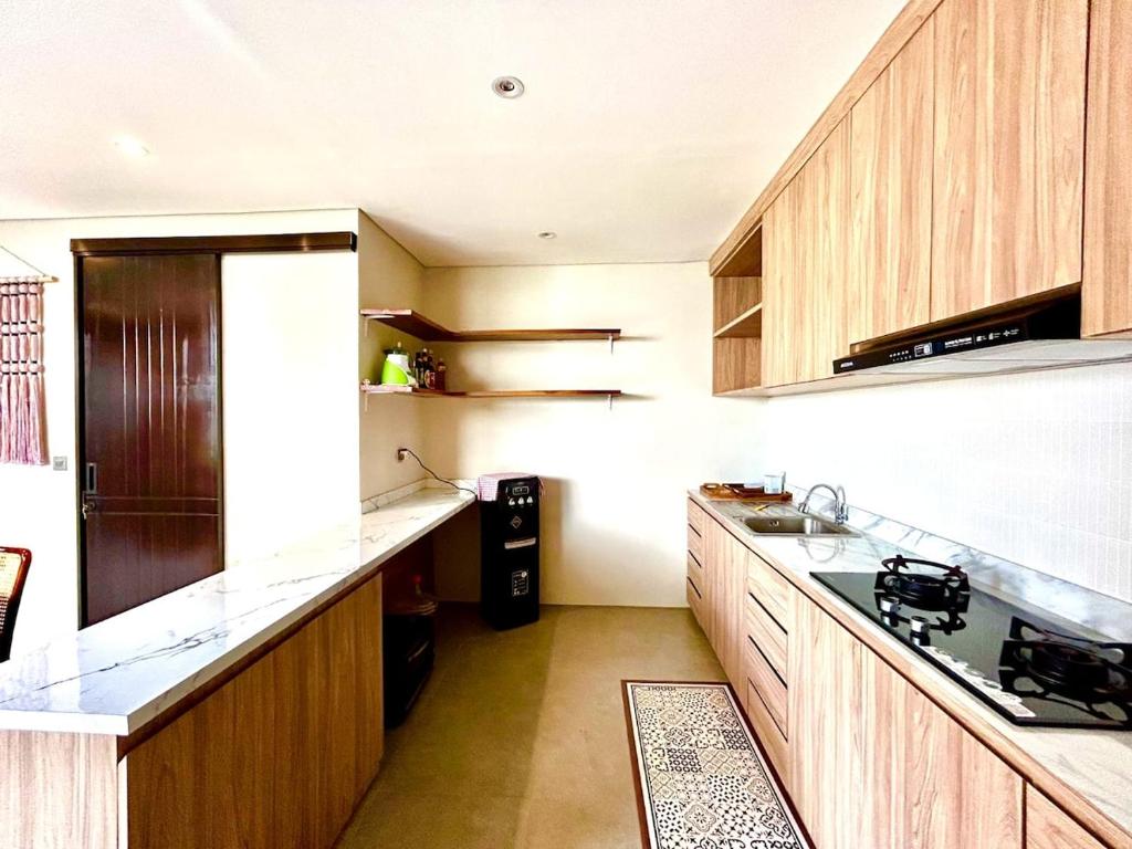 a large kitchen with wooden cabinets and a refrigerator at SanSan Home in Jimbaran