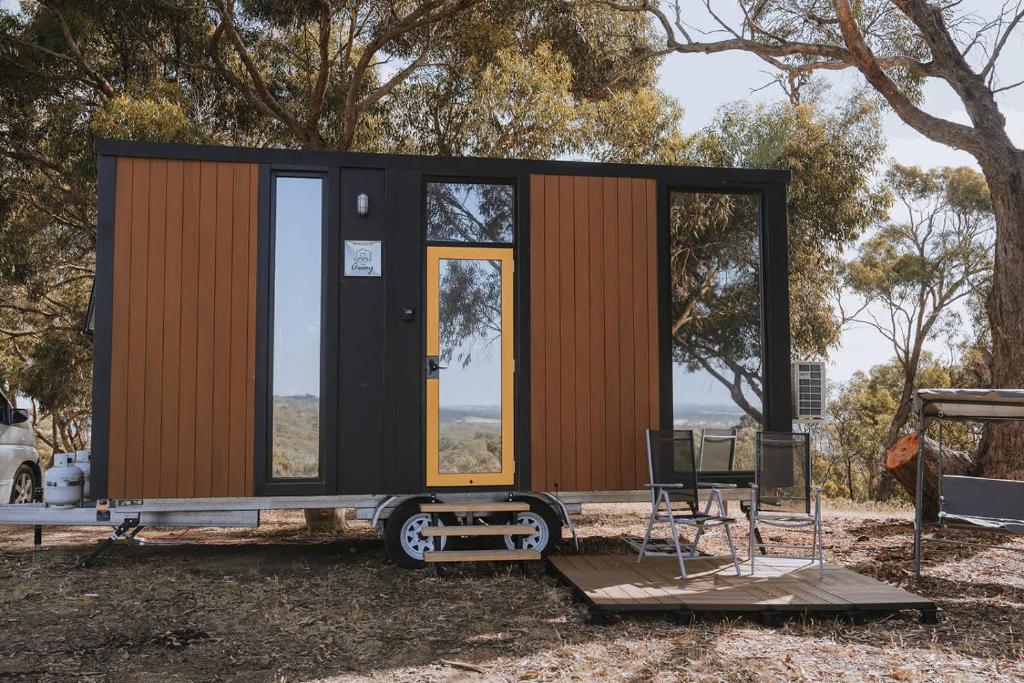 a tiny house on a trailer with a table and chairs at Tallarook Hilltop Tiny House 3 by Tiny Away in Tallarook