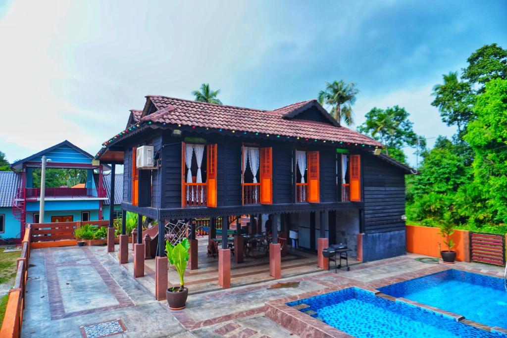 a house with a pool in front of it at Pondok Panglima Awang in Pantai Cenang