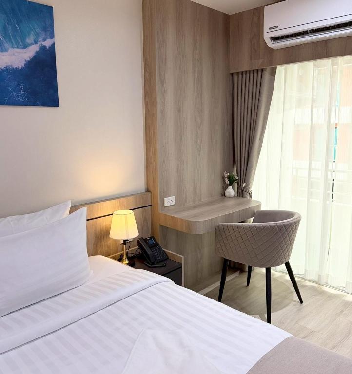 a hotel room with a bed and a chair and a window at Indigo Hotel Hatyai 2 Khet 8 in Sathani Hat Yai
