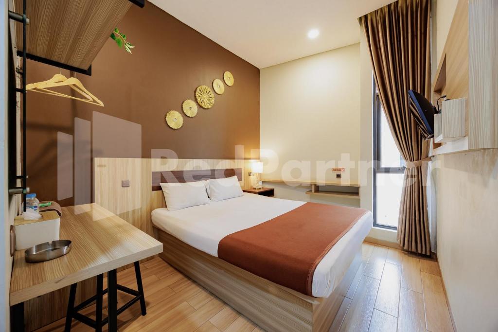 a bedroom with a bed and a desk and a window at Hotel Gandamanah Mitra RedDoorz in Bekasi