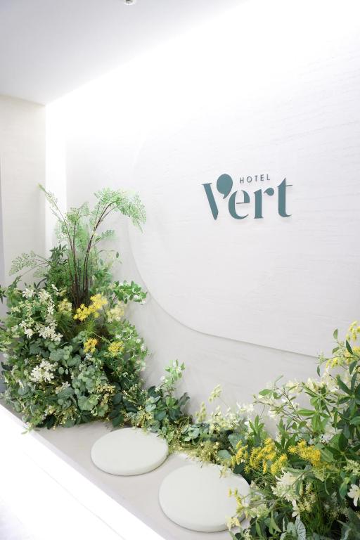 a white wall with three white plates and flowers at Hotel Vert in Seoul