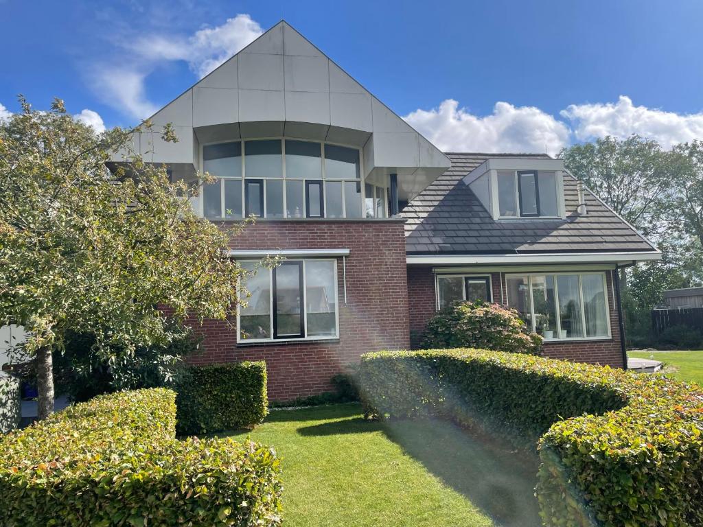 a large house with bushes in front of it at Gastenverblijf Buitenplaats Wergea contactloos inchecken in Naarderburen