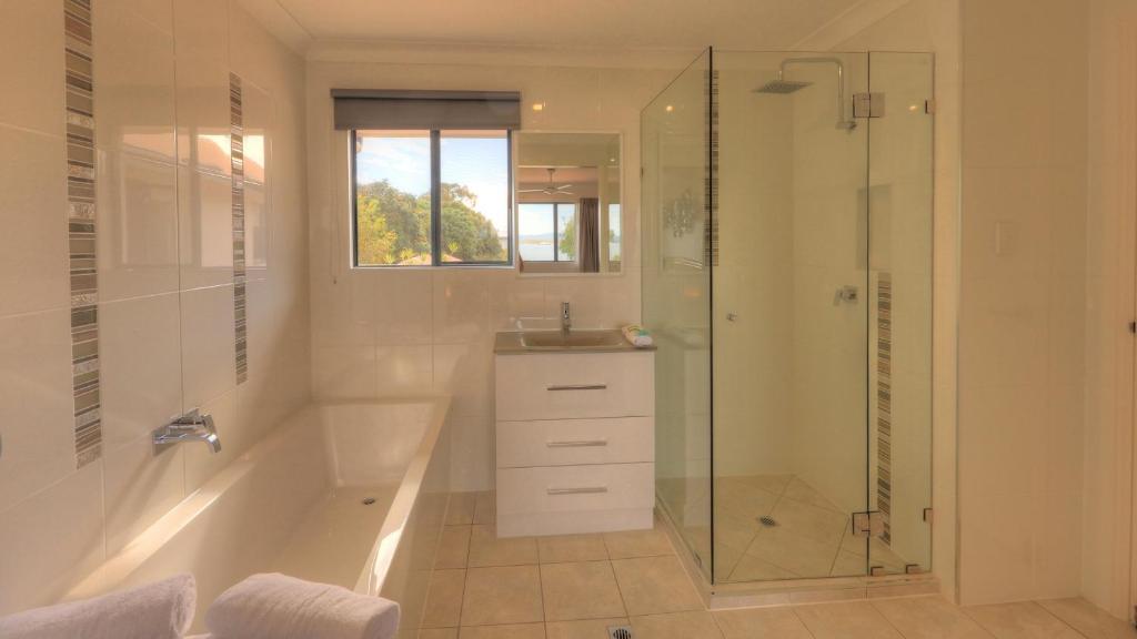 a bathroom with a shower and a tub and a sink at Dolphin Waters in Tin Can Bay