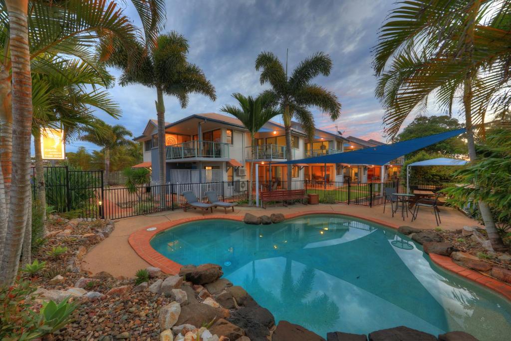 a house with a swimming pool and palm trees at Dolphin Waters in Tin Can Bay