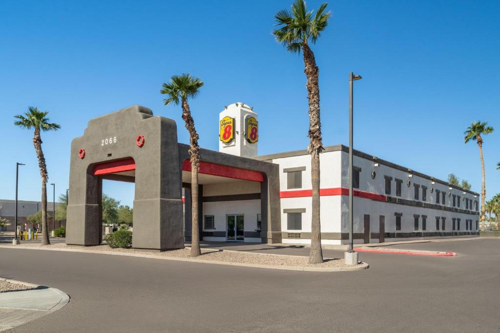 a building with palm trees in front of a street at Super 8 by Wyndham Casa Grande in Casa Grande