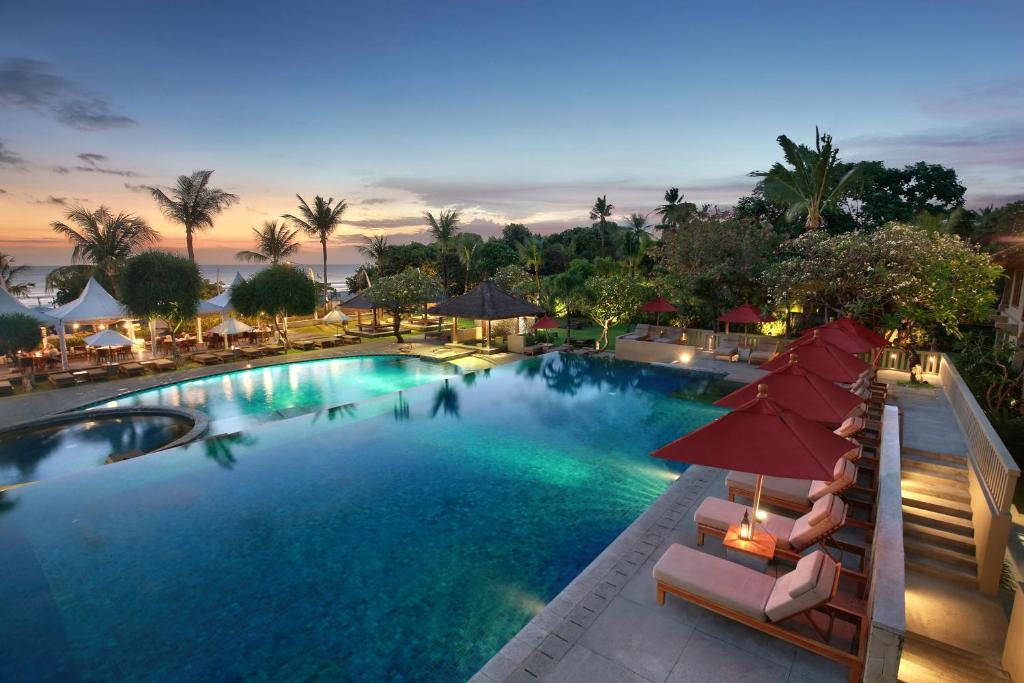 een uitzicht over een zwembad met parasols bij Bali Niksoma Boutique Beach Resort in Legian