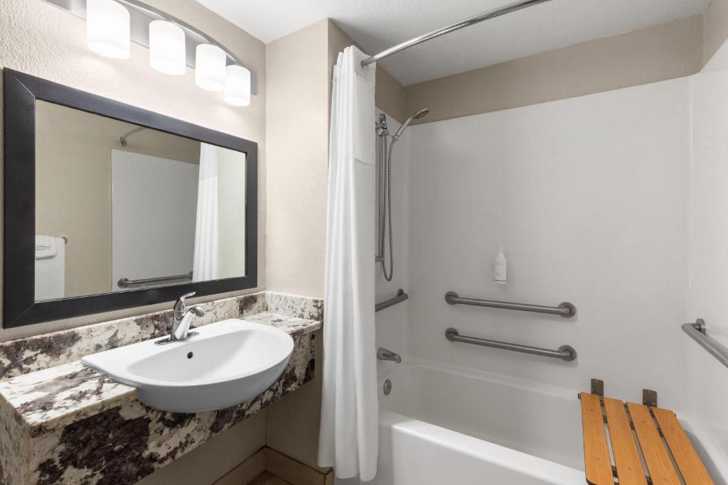 a bathroom with a sink and a tub and a mirror at Days Inn by Wyndham Charleston WV in Charleston