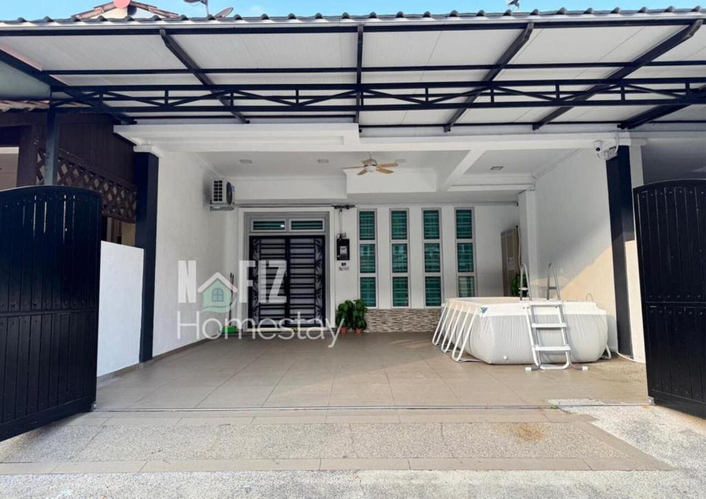 an open garage with a table in front of a building at NAFIZ Pool Homestay Melaka - Fully AC 4 Rooms with 3 Toilets, PS4 in Kampong Alor