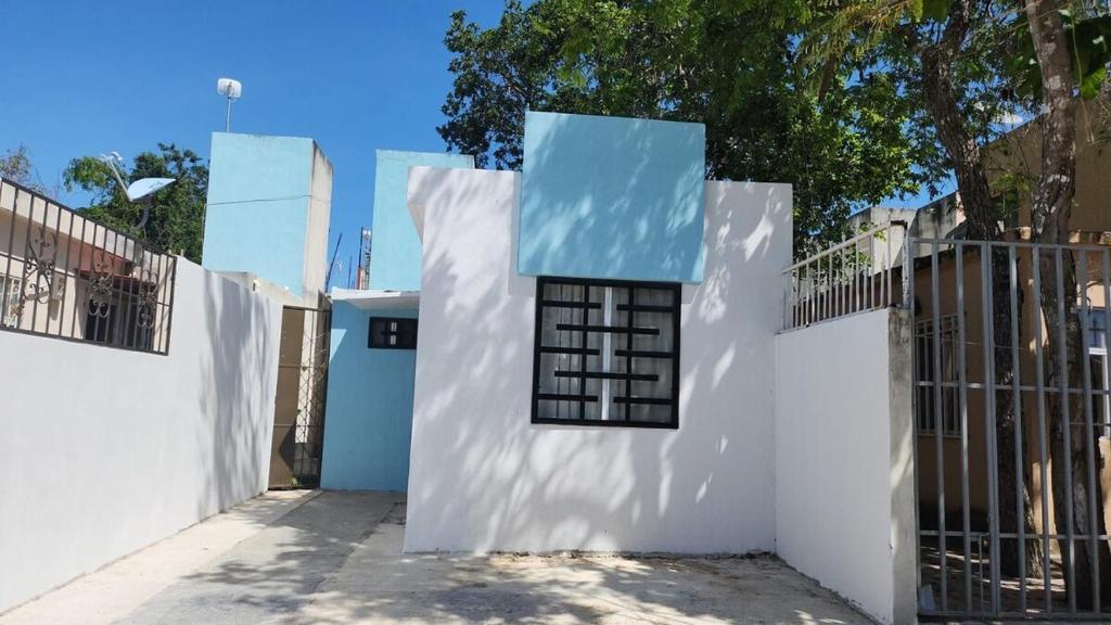 a white house with a blue roof at Casita Puerto Maya in Puerto Aventuras