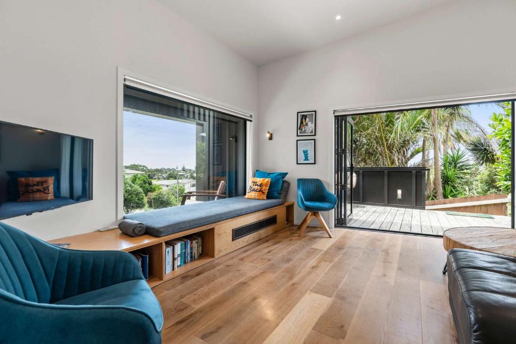 a living room with a couch and a large window at Up Above The Crescent in Waihi Beach