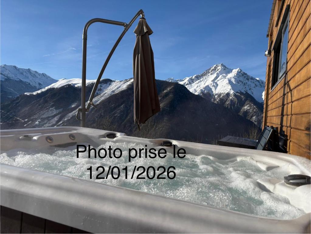 a bath tub with an umbrella and mountains in the background at Tiny House tout confort au cœur des Pyrénées calme, vue et détente in Grailhen