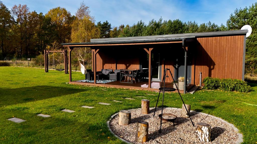 a small cabin with a porch in a field at WestfalowaChatka domek z jacuzzi in Sasino