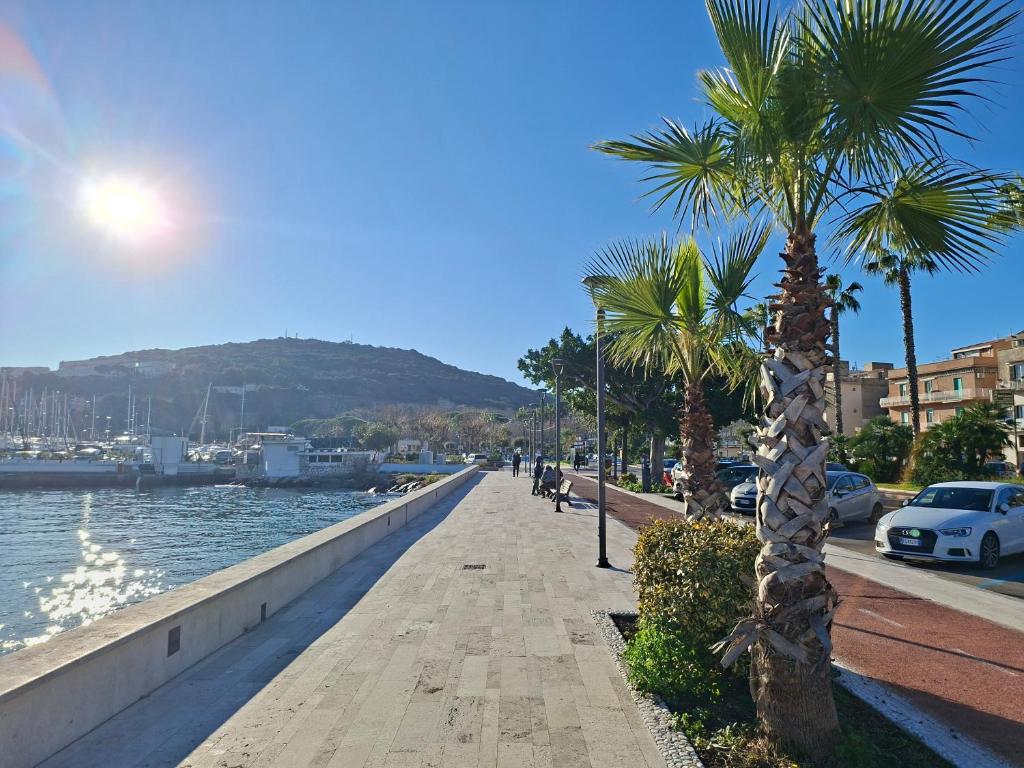 a sidewalk next to the water with palm trees at Aria di Mare Gaeta in Gaeta