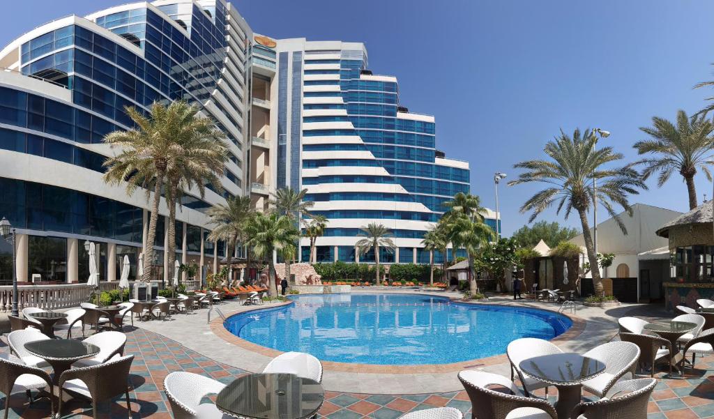 - une piscine avec des chaises longues et un bâtiment dans l'établissement Elite Resort & Spa, à Manama