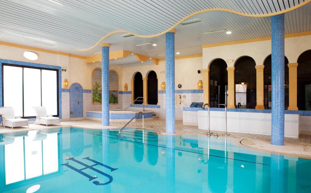 a large swimming pool with blue columns in a building at Hotel Jerez &amp; Spa in Jerez de la Frontera