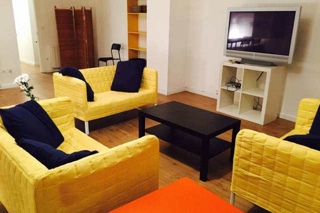 ein Wohnzimmer mit gelben Sofas und einem TV in der Unterkunft Apartamentos Coso in Saragossa