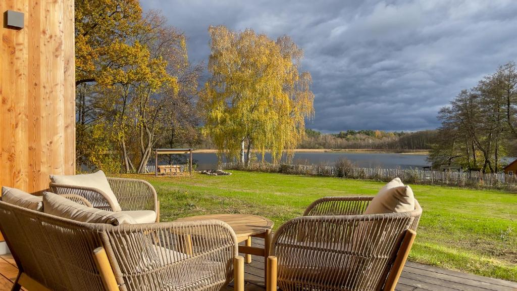 three chairs and a table on a deck with a lake at Villa SEE la vie in Rheinsberg