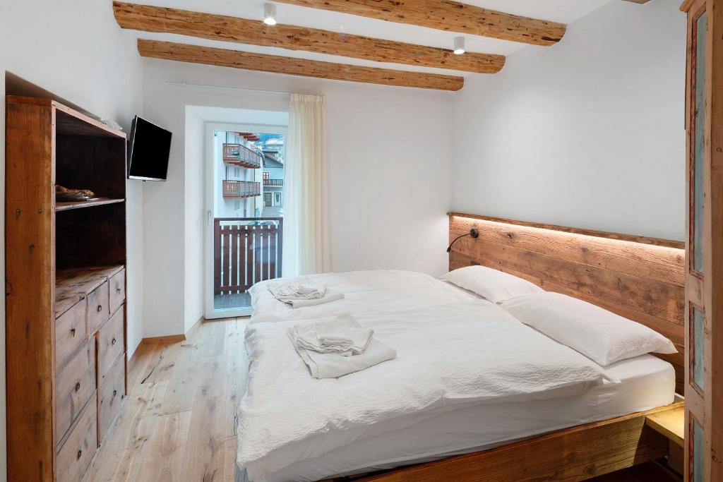a bedroom with a large white bed with a wooden headboard at Casa Patty Moena in Moena